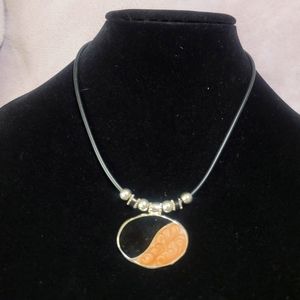 Necklace with black cord has a black and brown pendant with glitter, it is very